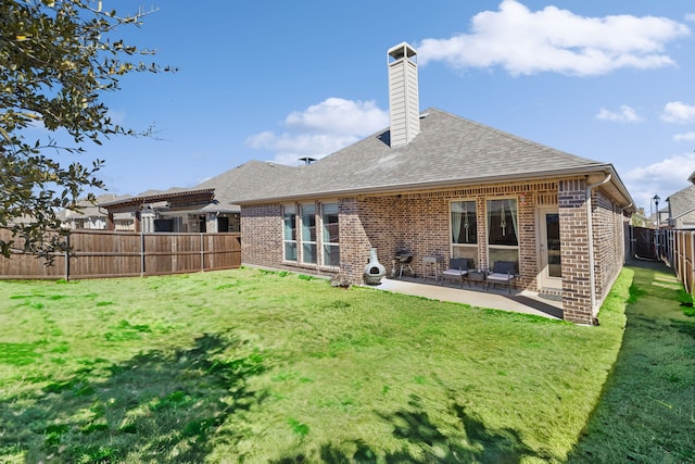 rear view of property with brick siding, a fenced backyard, a lawn, and a patio area