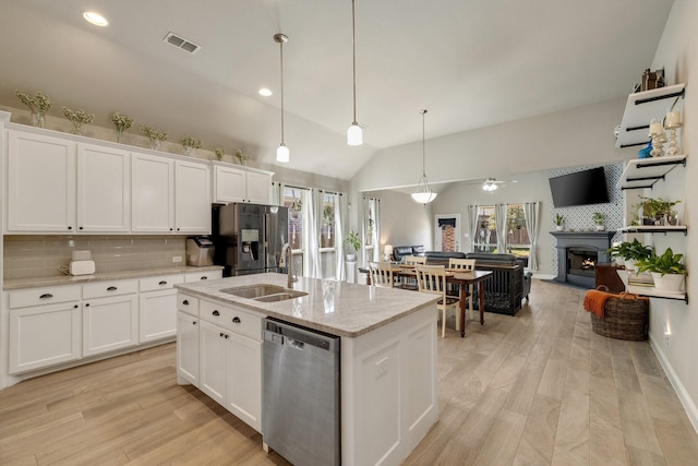 kitchen with visible vents, backsplash, a lit fireplace, stainless steel appliances, and a sink