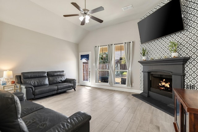 living area with visible vents, a large fireplace, light wood-style floors, and baseboards