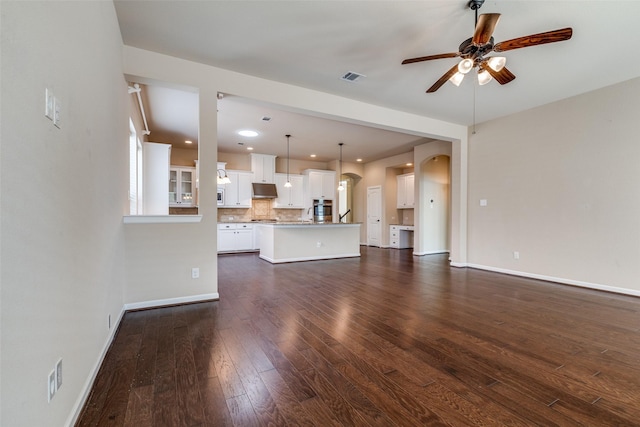 unfurnished living room with dark wood finished floors, visible vents, baseboards, and ceiling fan