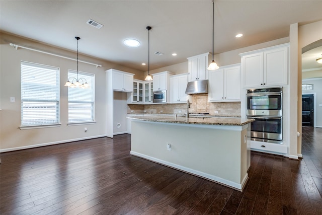 kitchen with visible vents, under cabinet range hood, dark wood-style floors, stainless steel appliances, and decorative backsplash