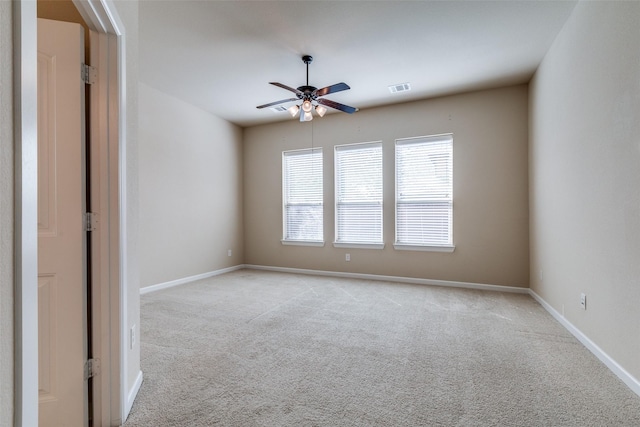 empty room featuring visible vents, baseboards, light colored carpet, and ceiling fan