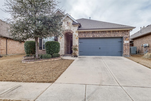 view of front facade with brick siding, central air condition unit, concrete driveway, a garage, and stone siding