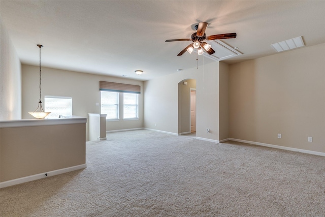 unfurnished room featuring visible vents, baseboards, ceiling fan, light colored carpet, and arched walkways