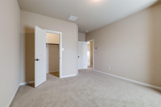 unfurnished bedroom with visible vents, light carpet, a closet, baseboards, and a spacious closet