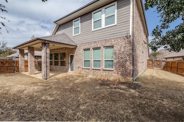 rear view of house with a gate, brick siding, a fenced backyard, and a patio area