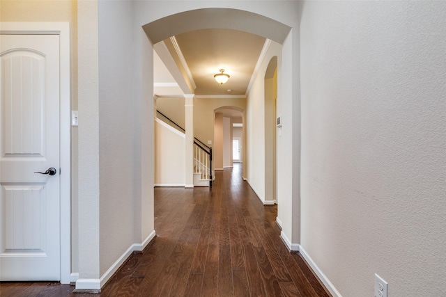 hall featuring stairway, baseboards, dark wood finished floors, arched walkways, and crown molding