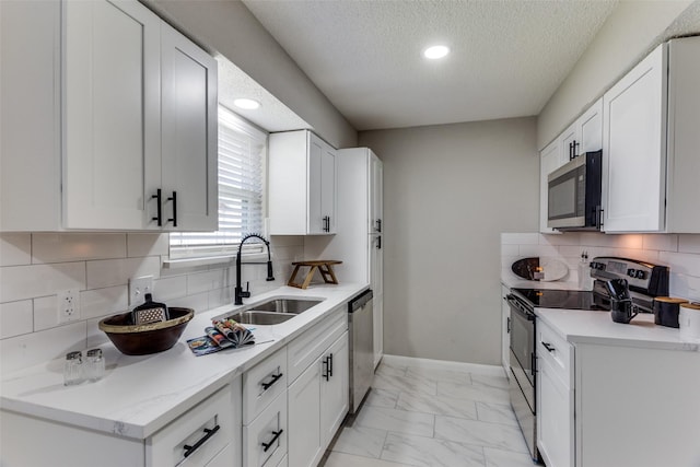 kitchen featuring baseboards, a sink, light countertops, appliances with stainless steel finishes, and marble finish floor