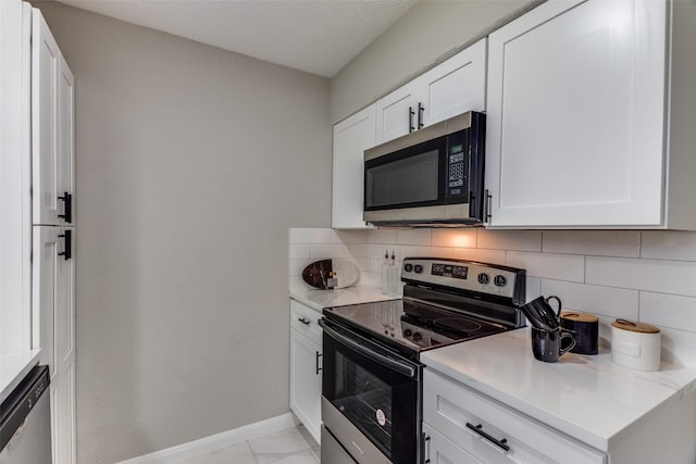 kitchen with baseboards, stainless steel appliances, decorative backsplash, white cabinets, and marble finish floor