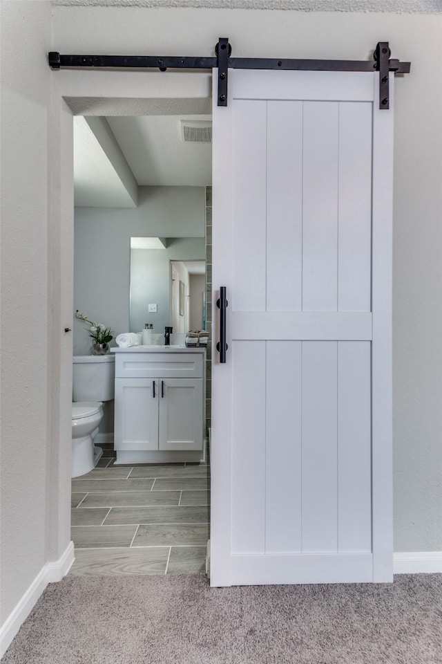 bathroom featuring visible vents, baseboards, toilet, carpet flooring, and vanity