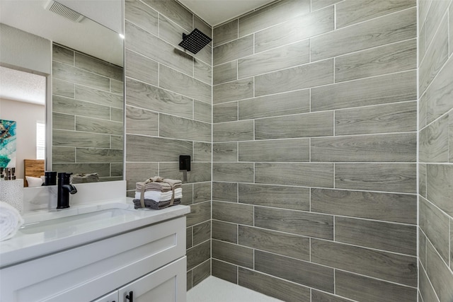 full bath with visible vents, tiled shower, and vanity