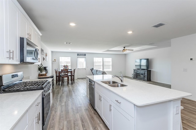 kitchen with visible vents, a sink, open floor plan, stainless steel appliances, and light wood finished floors