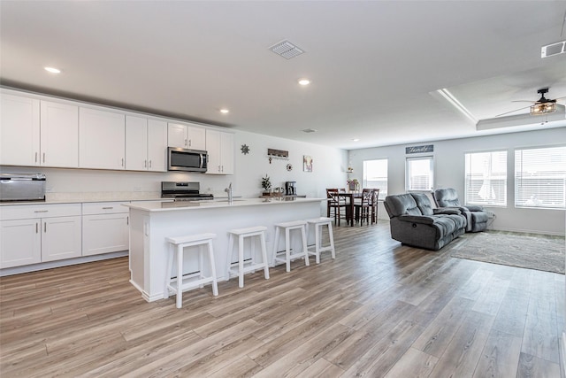 kitchen with visible vents, a kitchen breakfast bar, open floor plan, stainless steel appliances, and light wood finished floors