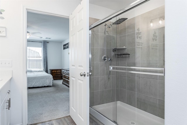 bathroom featuring a stall shower, wood finished floors, ensuite bath, ceiling fan, and vanity