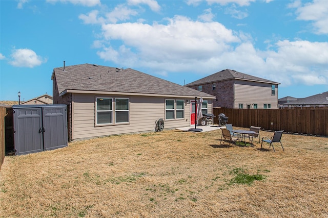 back of property featuring a storage unit, an outbuilding, a fenced backyard, and a yard