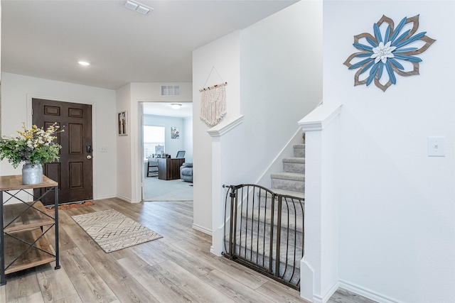 foyer featuring stairs, wood finished floors, visible vents, and baseboards