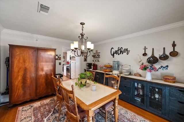 dining space with an inviting chandelier, wood finished floors, visible vents, and ornamental molding