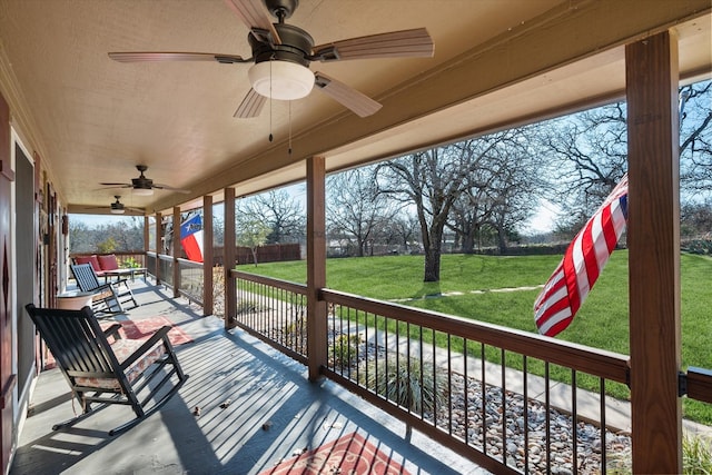 wooden deck featuring a lawn and a ceiling fan