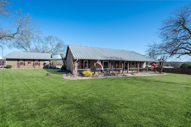 rear view of property with metal roof, a yard, and fence