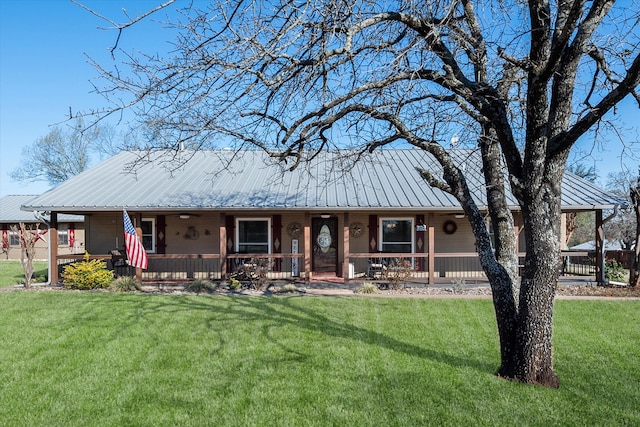 view of front of property featuring covered porch, metal roof, and a front lawn