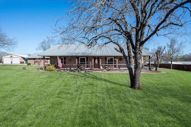 view of front of property featuring a front yard, a garage, covered porch, and metal roof