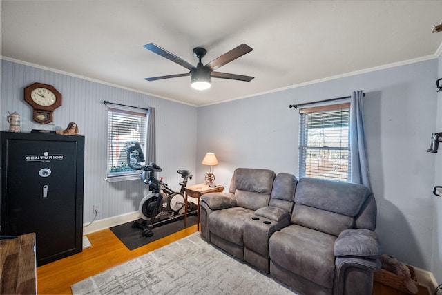 living room with ornamental molding, wood finished floors, baseboards, and ceiling fan