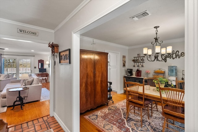 dining room featuring visible vents, crown molding, baseboards, wood finished floors, and a notable chandelier