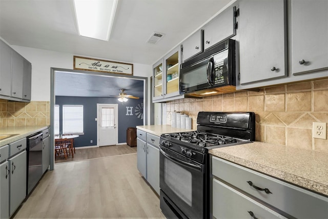 kitchen with visible vents, black appliances, gray cabinets, light wood-style floors, and light countertops