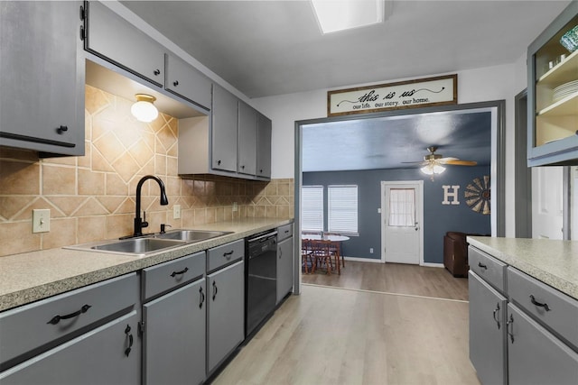 kitchen featuring light countertops, light wood-type flooring, black dishwasher, gray cabinets, and a sink