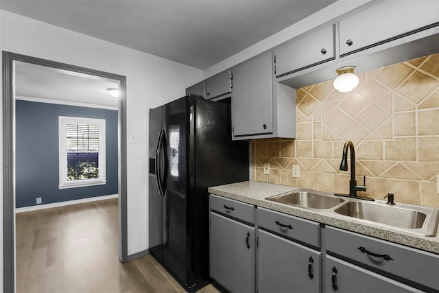 kitchen with a sink, black refrigerator with ice dispenser, backsplash, and gray cabinets