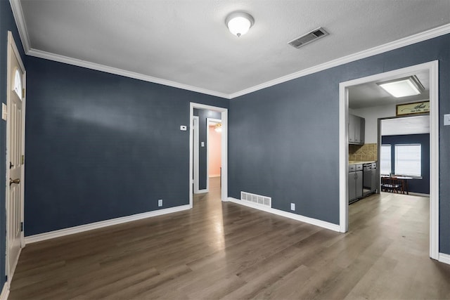 empty room featuring visible vents, crown molding, and wood finished floors