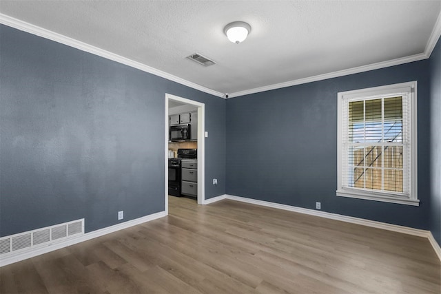 unfurnished room featuring visible vents, baseboards, wood finished floors, and ornamental molding