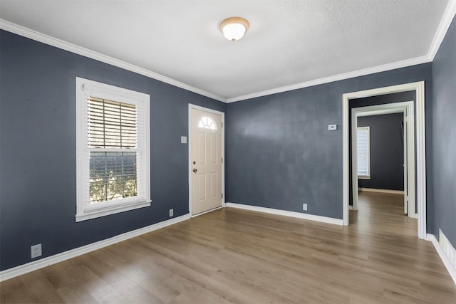 foyer featuring crown molding, wood finished floors, baseboards, and a textured ceiling