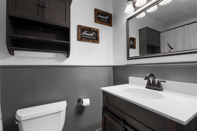 full bath featuring vanity, toilet, and wainscoting