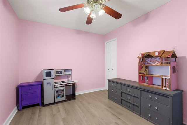 playroom featuring a ceiling fan, light wood-style floors, and baseboards