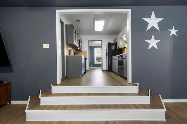 kitchen with dishwashing machine, light wood-style flooring, freestanding refrigerator, and baseboards