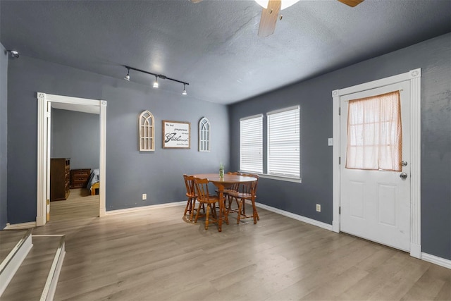 dining space featuring wood finished floors, baseboards, and a textured ceiling