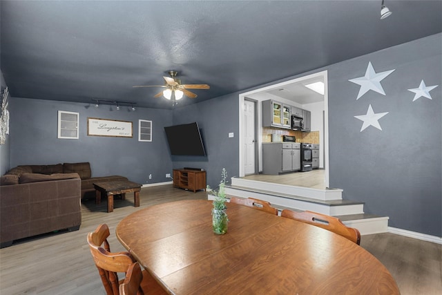 dining space featuring baseboards, light wood-type flooring, and ceiling fan