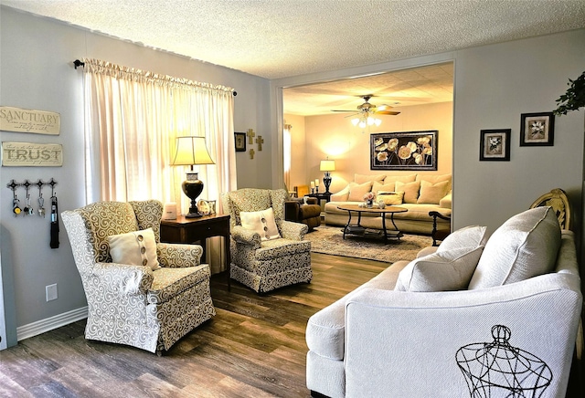 living room with baseboards, a textured ceiling, dark wood-style floors, and a ceiling fan