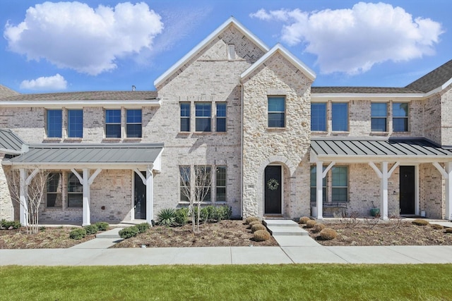 townhome / multi-family property with a standing seam roof, brick siding, and metal roof