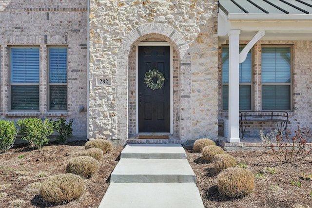 view of exterior entry with stone siding and brick siding