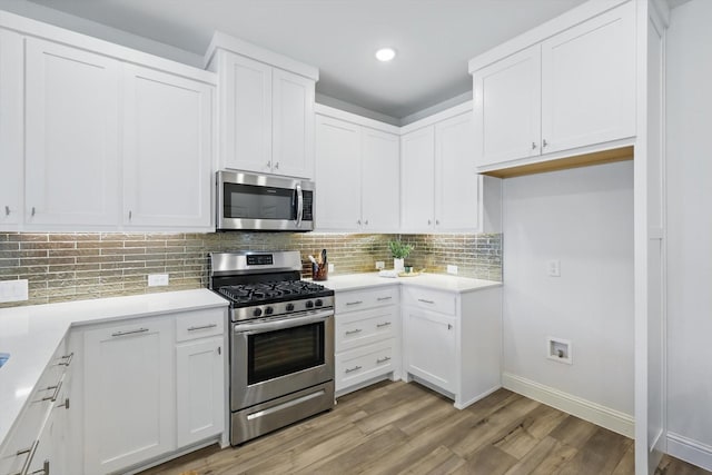 kitchen with decorative backsplash, light wood-style floors, white cabinetry, and appliances with stainless steel finishes