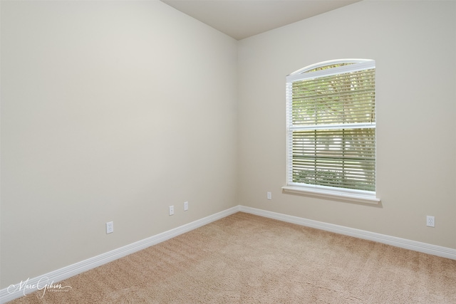 spare room with light colored carpet and baseboards