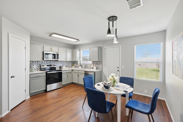 kitchen featuring visible vents, gray cabinets, wood finished floors, appliances with stainless steel finishes, and decorative backsplash