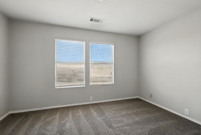 spare room with baseboards, visible vents, and dark carpet