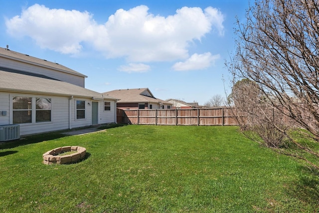 view of yard with a fire pit, fence, and central AC