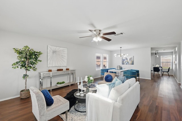 living area featuring visible vents, ceiling fan with notable chandelier, baseboards, and dark wood-style flooring