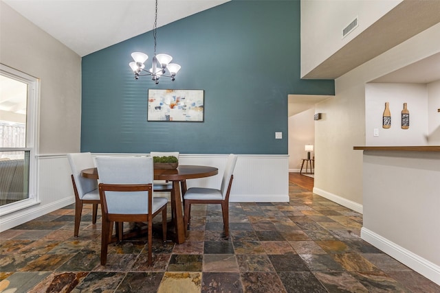 dining area featuring visible vents, a notable chandelier, stone finish flooring, wainscoting, and baseboards