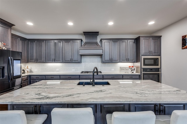 kitchen featuring a kitchen breakfast bar, appliances with stainless steel finishes, custom range hood, and a sink