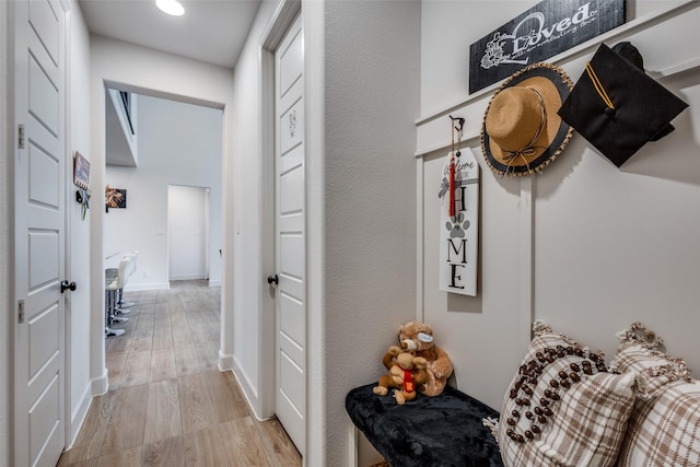 corridor featuring light wood-style flooring and baseboards